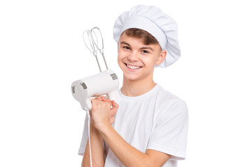 Wall Mural - Happy teen boy in chef hat holding mixer, isolated on white background. Portrait of cute smiling child having fun with egg beater. Tools and equipment for cooking.