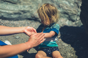 Wall Mural - Young mother applying suncream on her toddler