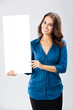 © vgstudio - Happy smiling beautiful young businesswoman showing blank sign board with empty copy space area for some slogan or advertising text message, on grey color background