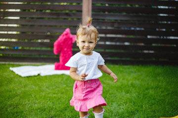 Wall Mural - Happy girl runs on green field dressed in pink.