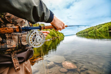 Wall Mural - Fisherman using rod fly fishing in mountain river