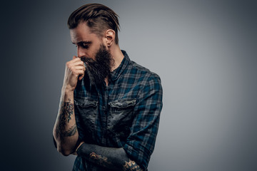 Bearded skinny man with tattooes feels dispair and sorrow while thinking about life.