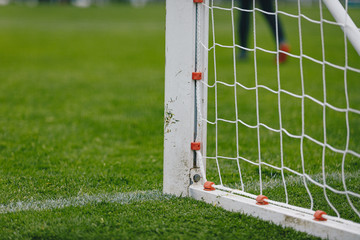 Football soccer goal. Post of football goal and white net in the foreground. Soccer stadium in the background. Summer sunny day