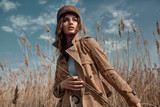 Fototapeta Tulipany - Beautiful Young Stylish Girl in Trench Coat Walking Autumn or Spring street. Autumn outdoor fashion.