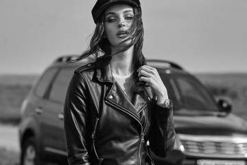 High fashion portrait of brunette woman outside in leather black jacket and trendy hat. Outdoor fashion.