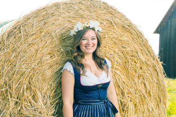 Wall Mural - Frau in Tracht vor einem Strohballen an einem sonnigem Tag in bayern