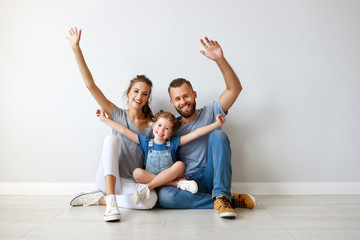 Wall Mural - happy family mother father and child  near an empty wall.