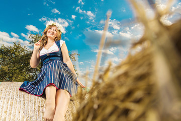 Wall Mural - Frau in Tracht vor einem Strohballen an einem sonnigem Tag in bayern