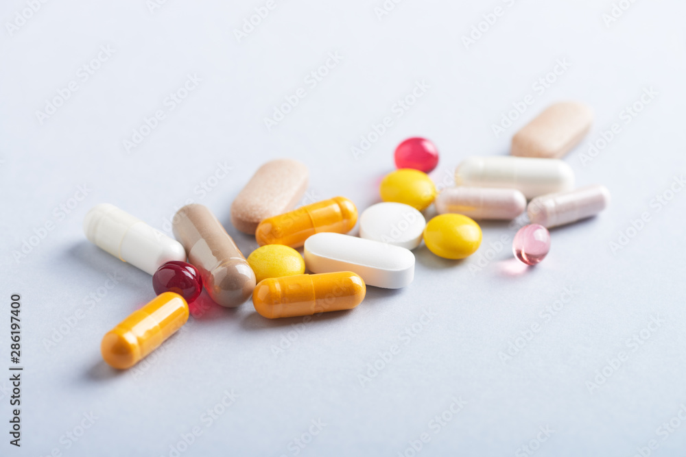 Vitamins and supplements on bright paper background. Concept for a healthy dietary supplementation. Close up. Copy space. 