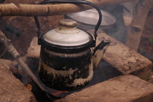An Old Teapot On A Fireplace In Forest