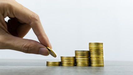 Wall Mural - Making money and money investment concept. A man hand holding coin over stack of coins on wood on white background. Depicts long-term investment And wealth and financial stability.