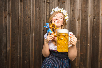 Poster - Junge Frau mit Bierkrug und Brezel auf einem Holzhintergrund .Oktoberfest-Konzept 