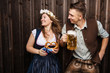 © karepa - Junge Frau und mann mit Bierkrug und Brezel auf einem Holzhintergrund .Oktoberfest-Konzept