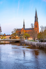 Wall Mural - Sunset view of Uppsala cathedral reflecting on river Fyris in Sweden