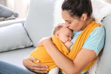 Young mother with little baby in sling at home