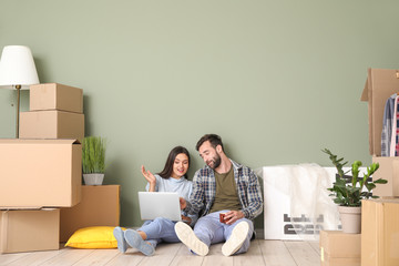 Poster - Young couple with cardboard boxes and laptop after moving into new house