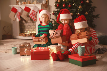 Cute little children opening Christmas gifts at home