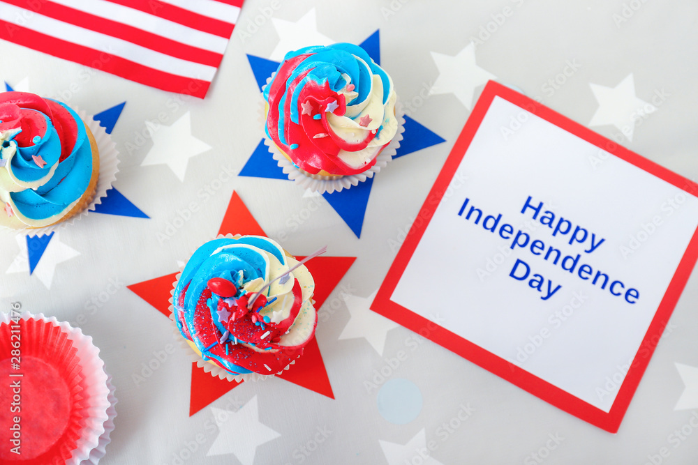 Tasty patriotic cupcakes and card for Independence Day on table