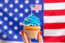 Female Hand With Tasty Patriotic Cupcake Against USA Flag