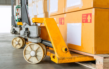 Wall Mural - closeup yellow hand pallet truck with stack cardboard boxes on wooden pallet.