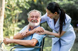 © Sasils Production - Caring nurse with senior man sitting on wheelchair in gaden. Asian woman, caucasian man. Big smile.