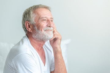 Senior man sitting in bed. Caucasian male. Thinking and smile.