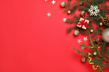 fir branches with christmas decoration on red background, flat lay. space for text