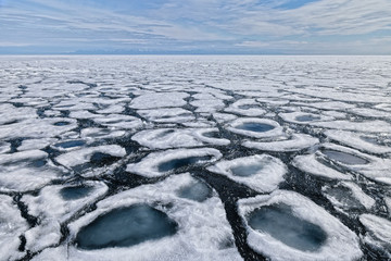 Beautiful melting figured ice floes with blue crystal clear water in center. Scenic northern spring landscape or background in soft pastel colors