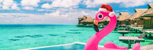 Christmas Beach Summer Vacation Winter Holiday Destination Panoramic Banner. Pink Flamingo Pool Float With Santa Hat Travel Background For Winter Holidays.
