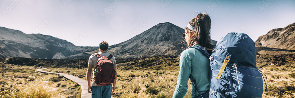 New Zealand Hiking Couple Backpackers Tramping At Tongariro National Park. Male and female hikers hiking by Mount Ngauruhoe. People living healthy active lifestyle outdoors - obrazy, fototapety, plakaty 