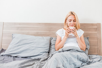 Wall Mural - Woman sitting on bed drinking coffee