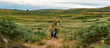 © luka - Hikers in the grasslands with windmills in the background