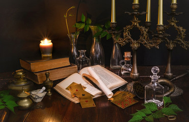 Cards, spell books and bottles of potions with dark candlesticks on a wooden table. Prediction of love in the future. Recipes of magic potions. Concept of clairvoyance, Fortune telling and alchemy