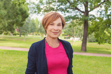 Wall Mural - Healthy senior woman walking in park. Older woman with red short haircut outdoors. Mature beauty, 60s