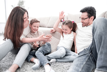 Wall Mural - parents play with children sitting on the carpet in the living room