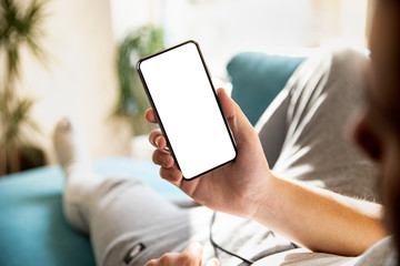 Wall Mural - man using smartphone blank screen frameless modern design while lying on the sofa in home interior
