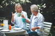 © Sasils Production - Family lunch outdoor. Couple of white senior man and woman sitting and talking to each other in tropical garden.