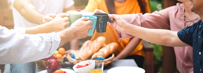 Family lunch outdoor. Married mix race couple with grand parents. White man, Asian pregnant woman with senior asian couple in tropical garden. Toasting pose. Banner frame with light leaks.