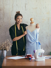 Confident freelance designer with cloth dummy in her workplace, lifestyle concept.