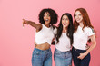 © Drobot Dean - Cheerful cute multi-ethnic girls friends posing isolated over pink wall background pointing.