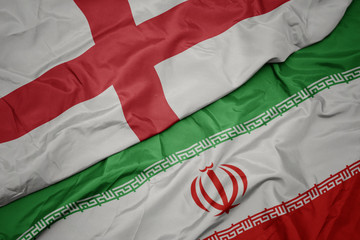 waving colorful flag of iran and national flag of england.