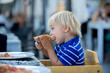 © Tomsickova - Toddler boy, eating pizza on the beach in restaurant