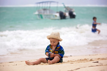 Sticker - Cute baby boy playing with beach toys on tropical beach