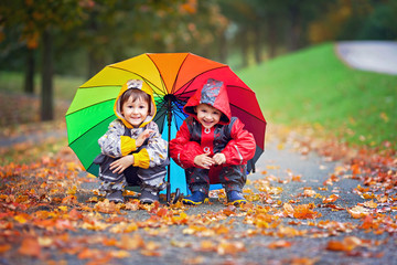 Poster - Two adorable children, boy brothers, playing in park with umbrella