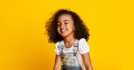 Laughing cute afro girl portrait, yellow background