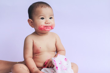 asian cute baby girl eating red dragon fruit. newborn baby on white background