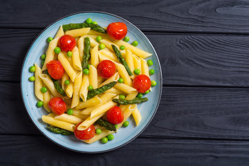 Penne pasta salad with asparagus , tomatoes and peas