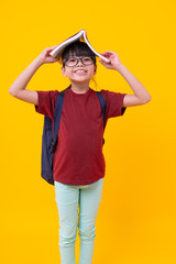 Portrait of Asian funny girl kid with book on head smiling, pretty Thai student in red shirt with glasses have attractive standing and looking camera, knowledge and wisdom