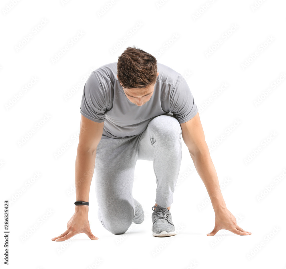 Sporty young man in crouch start position on white background