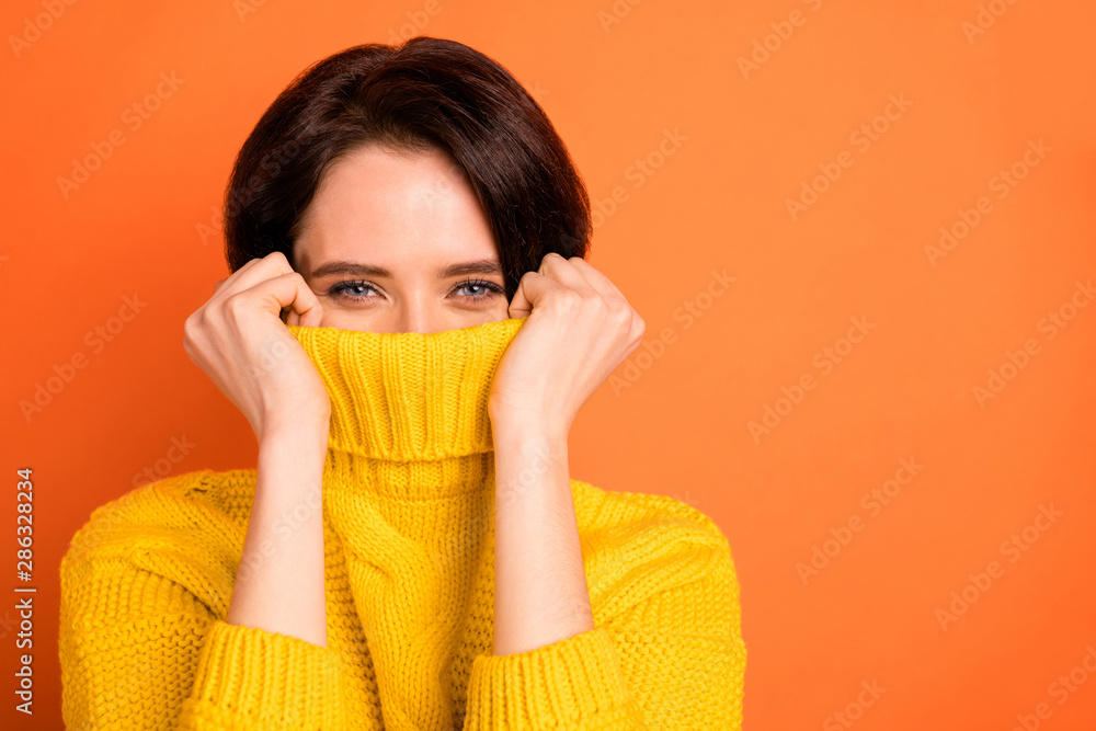 Close up photo of cute nice charming girl hiding from cold by wrapping up in collar while isolated with orange background - obrazy, fototapety, plakaty 